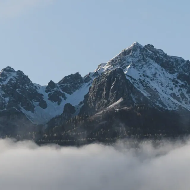 A snow-streaked ridge rising out of a thick bank of cloud.